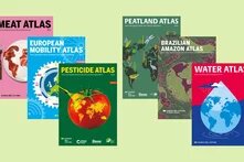 Seven colorful atlas covers with titles on meat, mobility, pesticides, peatlands, Amazon, water, and environmental data.