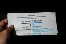 Hand hält Stimmzettel zur Bundestagswahl 2021 im Wahlkreis Bonn mit zwei markierten Kreuzen.