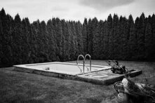 Schwarz-weiß Fotografie von einem Pool umringt von Hecken