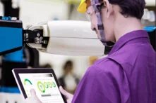 Arbeiter mit Helm im violetten Hemd mit einem Tablet in der Hand