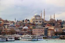 Blick über das Wasser auf Istanbul mit der Süleymaniye-Moschee, Fähren im Vordergrund und dicht bebautem Stadtgebiet.