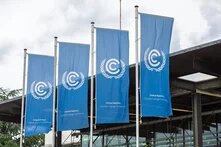 Four blue flags from the UN Climate Change Conference, featuring the logo and the text “United Nations Climate Change Conference,” in front of a building.