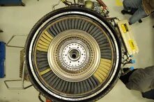 Top view of a gas turbine with a circular array of turbine blades and exposed mechanical components.