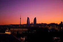 The dark skyline of Baku at sunset. The sky ranges from orange to purple.