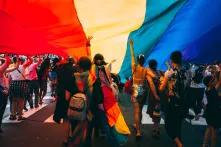 People walk under the rainbow flag