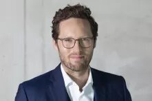 Porträt von Jan Philipp Albrecht: kurzes braunes Haar, Brille, drei Tage Bart, weißes Hemd, blaues Jacket