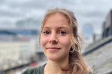 Nahaufnahme einer lächelnden Frau mit Nasenring. Verschwommener Stadt-Hintergrund.