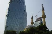 a newly built skyscraper overshadows an old mosque near martyr's alley in baku