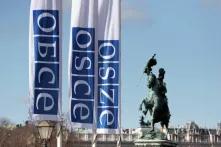 Flaggen mit dem OSZE-Logo auf Russisch, Englisch und Deutsch vor der Hofburg in Wien.