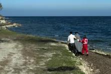 Member of Greek Red Cross helps an Afghan refugee who has just arrived from Turkey with an inflatable boat in the area of airport of Mytilene, Lesvos Island, Greece