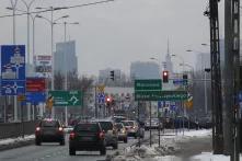 Straße mit Autos in Warschau, im Hintergrund die versmogte Stadt