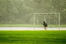 Kind im Regen auf der Schaukel