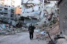 A man stands in front of rubble.