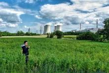 Ein Junge, stehend in grünem Feld, vor einem AKW