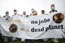 Lehren aus der Kohlekommission: Eine Gruppe in weiß gekleideter Protestant/innen hält ein Banner mit der Aufschrift "there are no jobs on a dead planet".