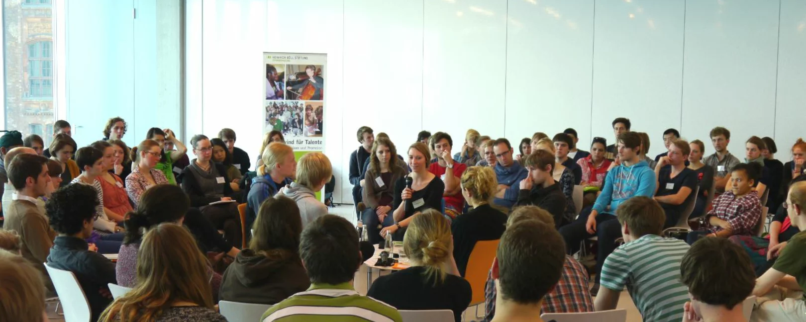 Veranstaltung des Studienwerkes. Viele Teilnehmende - von hinten in den Raum fotografiert.