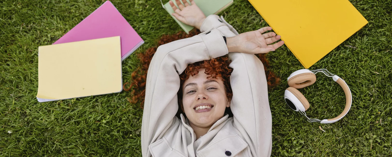 Studentin entspannt im Gras mit Büchern und Kopfhörern im Freien Modell freigegeben, Symbolfoto