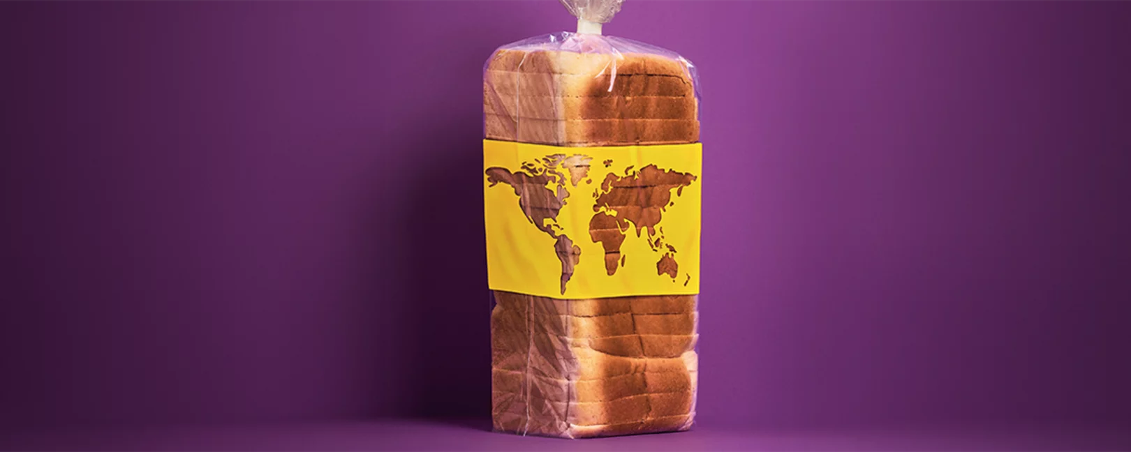 Ein in Plastik verpacktes, vorgeschnittenes Toastbrot steht vor einem violetten Hintergrund und trägt eine gelbe Banderole mit einer stilisierten Weltkarte.