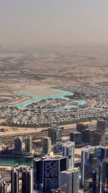 Blick aus Luft auf die Skyline von Dubai, dahinter sandige Böden und staubige Luft