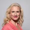Julia Leininger trägt einen pinken Sakko und blickt lächelnd in die Kamera