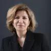 Joumana Seif blickt mit einem Lächeln in die Kamera vor einem dunklen Hintergrund