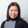 Lucia Siu blickt lächelnd in die Kamera vor einem weißen Hintergrund