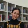 Adiya Akhmer steht in einer Bibliothek und lächelt