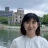 Shizuka Kuramitsu steht vor einem Fluss in der Stadt und lächelt