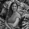Portrait of Carolina Gamazo Aramedia. Black and white image. She is standing among leaves.