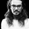 Black and white portrait of Erick Fariñas Torres with long hair and glasses. 