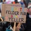 Menschen auf einer Demonstration mit einem Schild, auf dem steht: Bunte Felder für bunte Teller. 