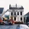 Ein abgebranntes Haus mit einem Feuerwehrauto davor.