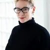 Porträt von Dani Kranz mit schwarzem Rollkragenpullover und Brille.