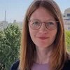 Dorthe Siegmund Foto: Eine Person mit langen, glatten Haaren und Brille steht im Freien vor Bäumen und Gebäuden im Hintergrund.