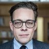 Konstantin von Notz Person mit Brille blickt frontal in die Kamera, Hintergrund unscharfes Bücherregal.