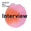  Ein pink-orangefarbener Kreis mit dem Wort "Interview" in Schwarz. Oben links das Logo der Heinrich-Böll-Stiftung.