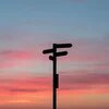 Ein Wegweiser mit mehreren Richtungen vor einem farbenfrohen Sonnenuntergangshimmel.