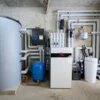 Heizungsraum mit einer modernen Heizungsanlage, Wärmespeicher, mehreren Rohren und einem blauen Druckbehälter.