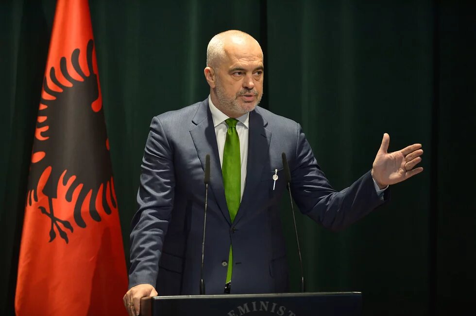 Der Premierminister Ed Rama nutzt die Corona-Krise für mediale Omnipräsenz Ed Rama, Premierminister von Albanien vor einem Rednerpult, dahinter die Fahne Albaniens
