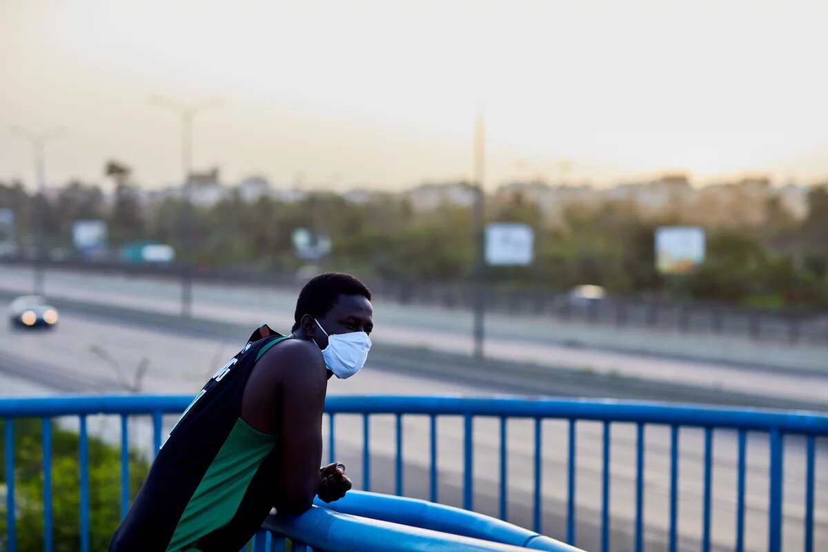 Migration in Senegal: Gesellschaftliche Visionen statt Kriminalisierung und Abschreckungsrhetorik People of Color mit Maske lehnt an Autobahn-Brückengeländer