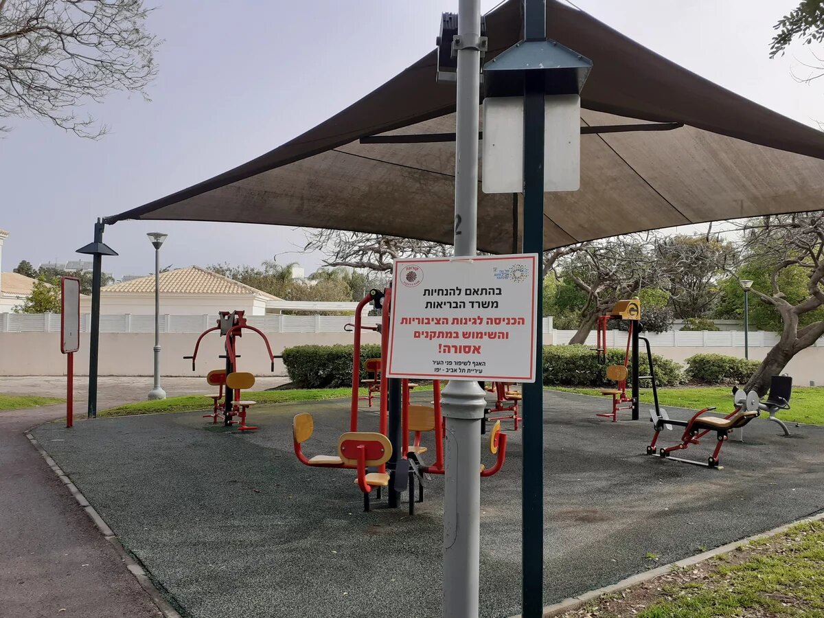 Ein geschlossener Park in Tel Aviv während der Covid19-Pandemie im März 2020 Ein Pavillon mit Fitnessgeräten in einem Park, davor ein Schild mit hebräischer Aufschrift