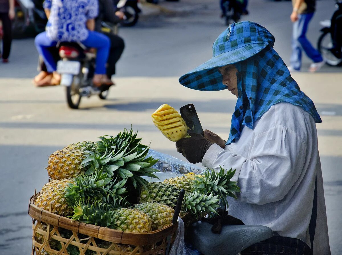 Ein Mensch schneidet Ananas an einer Straße