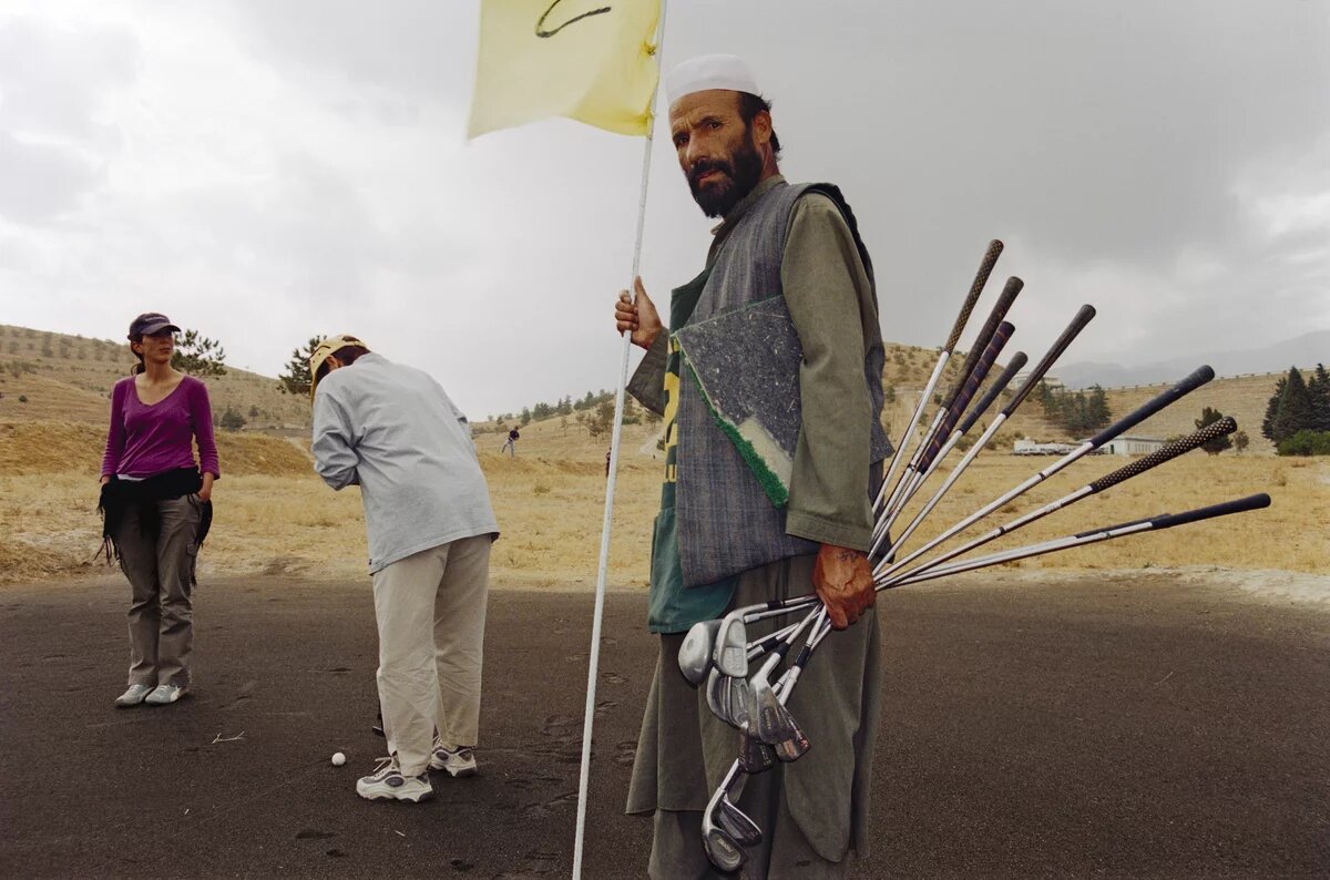 Ein Mann steht mit Golfschlägern auf einem Golfplatz