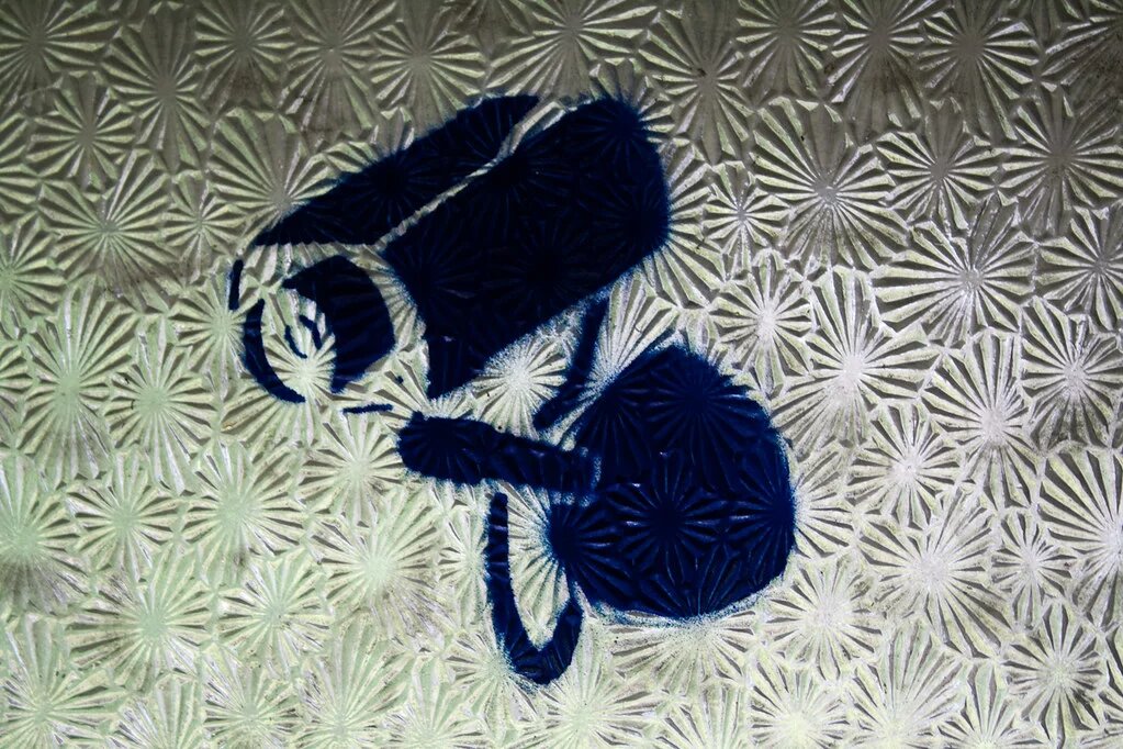 Surveillance Grafitti - aufgesprühte schwarze Kamera auf silbern gemusterten Hintergrund
