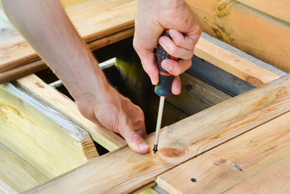 Handwerker dreht eine Schraube mit einem Schraubenzieher ein Handwerker dreht eine Schraube mit einem Schraubenzieher ein