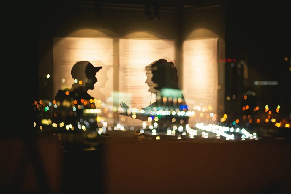 Silhouetten von zwei Personen, die sich im Dunkeln unterhalten.