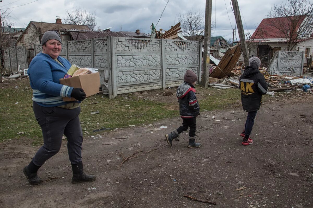 Eine Frau und zwei Kinder laufen durch Novoselivka, ein zerstörtes Dorf in der Ukraine. Eine Frau und zwei Kinder laufen durch Novoselivka, ein zerstörtes Dorf in der Ukraine.