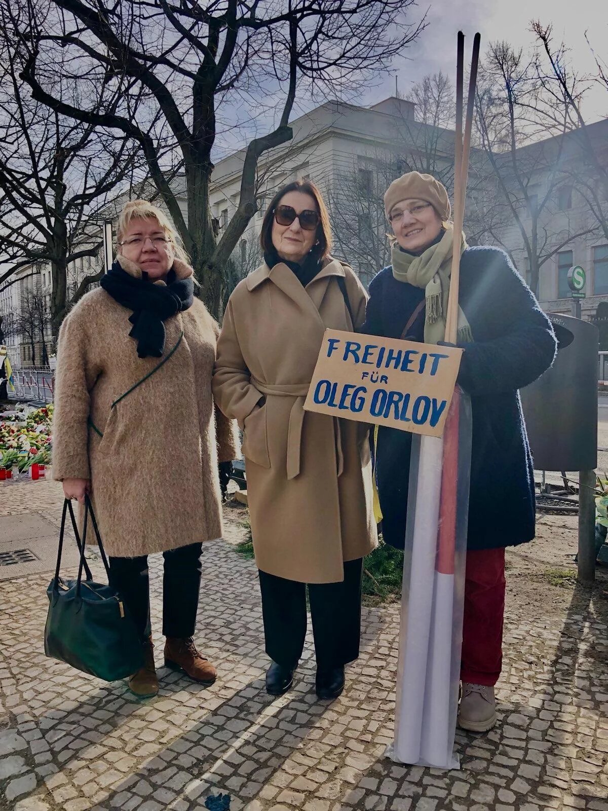 Lena Schemkova, Irina Scherbakova und Uta Gerlant von Memorial stehen vor der russischen Botschaft in Berlin und halten eine Schild hoch, auf dem steh "Freiheit für Oleg Orlov"