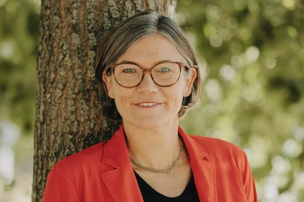 Christiane Benner Christiane Benner steht vor einem Baum in einem roten Jackett