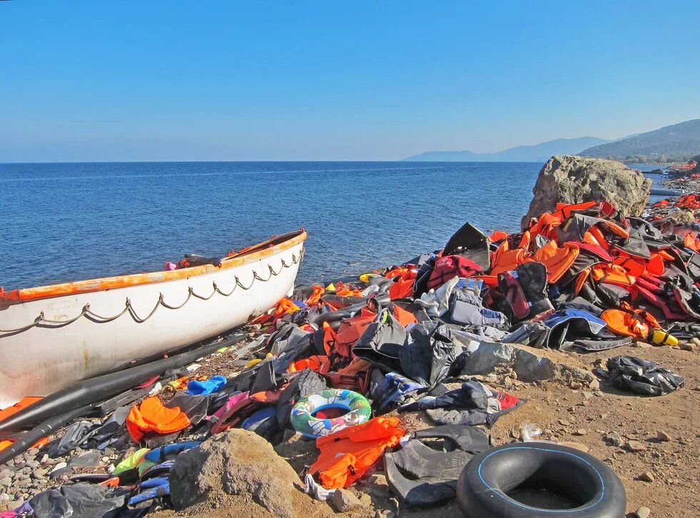 Verlassenes Flüchtlingsboot am Meeresufer von Lesbos (Griechenland) und unzählige Schwimmwesten am Strand Flüchtlingsboot am Meeresufer und unzählige Schwimmwesten am Strand